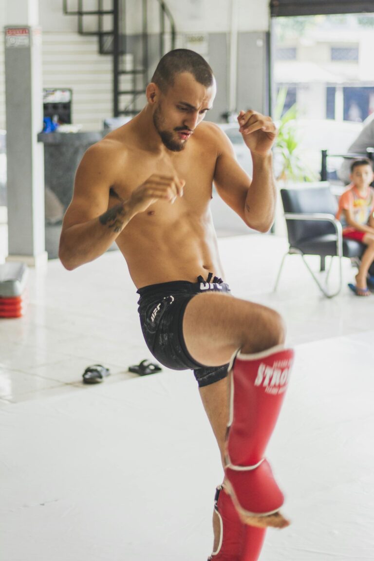 A male kickboxer trains passionately indoors, showing strength and focus.